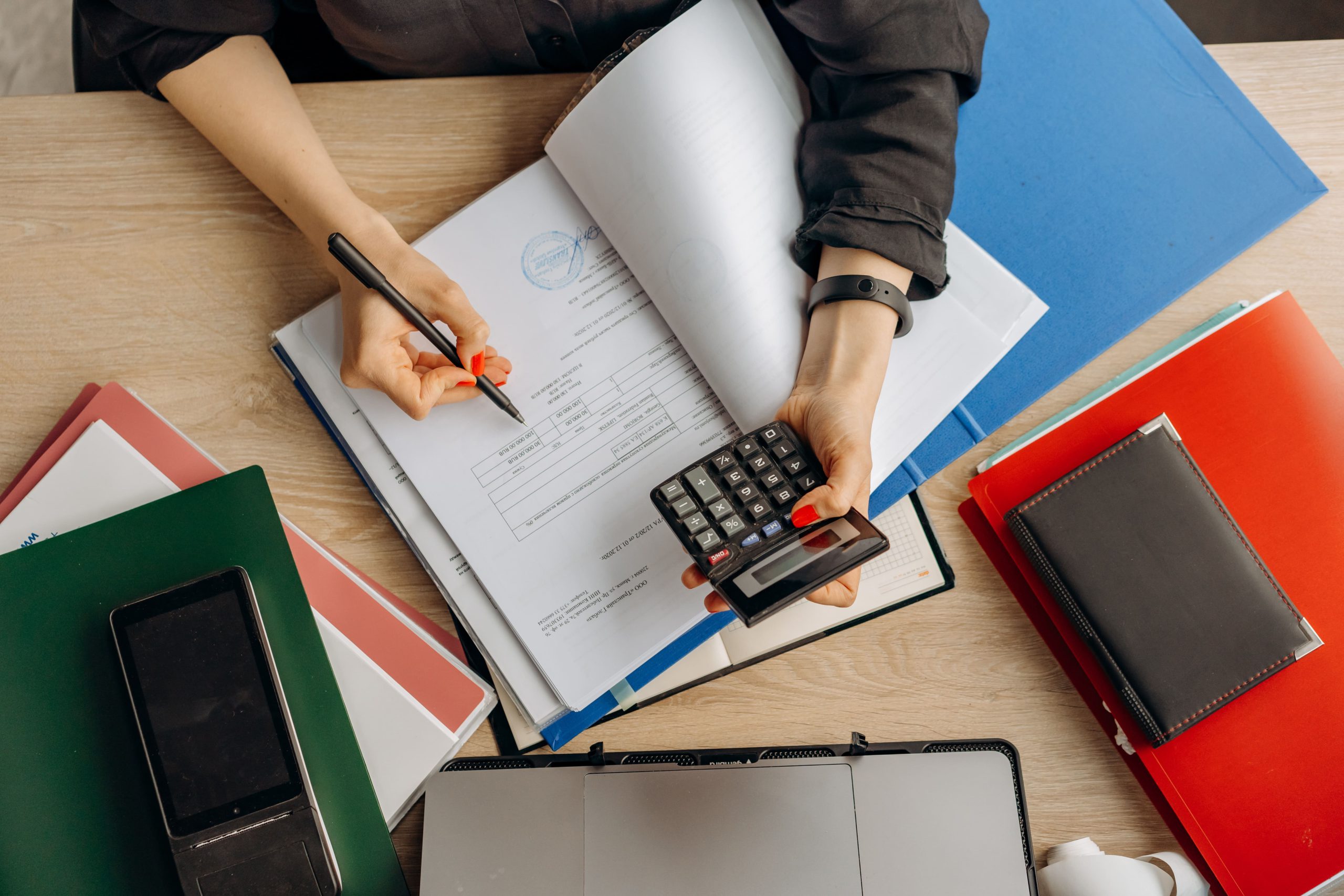 las manos de una mujer llenando un documento con una calculador a en una mano